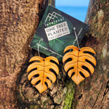 Wooden monstera earrings on a card with 'lovelevel' branding on a tree.