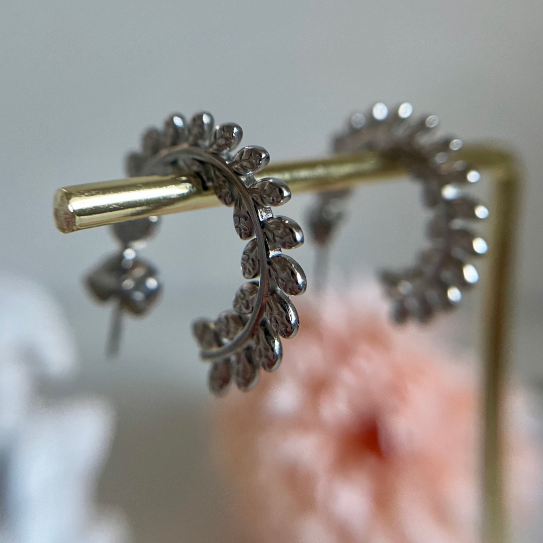 Silver hoop earrings draped over a golden bar with a blurred background.