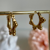 Golden-hoop earrings hanging from a golden bar.