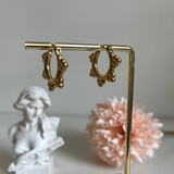Golden hoop earrings dangling from a golden bar