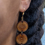Women wearing dangle/drop earrings with three wooden circles connected by gold rings.