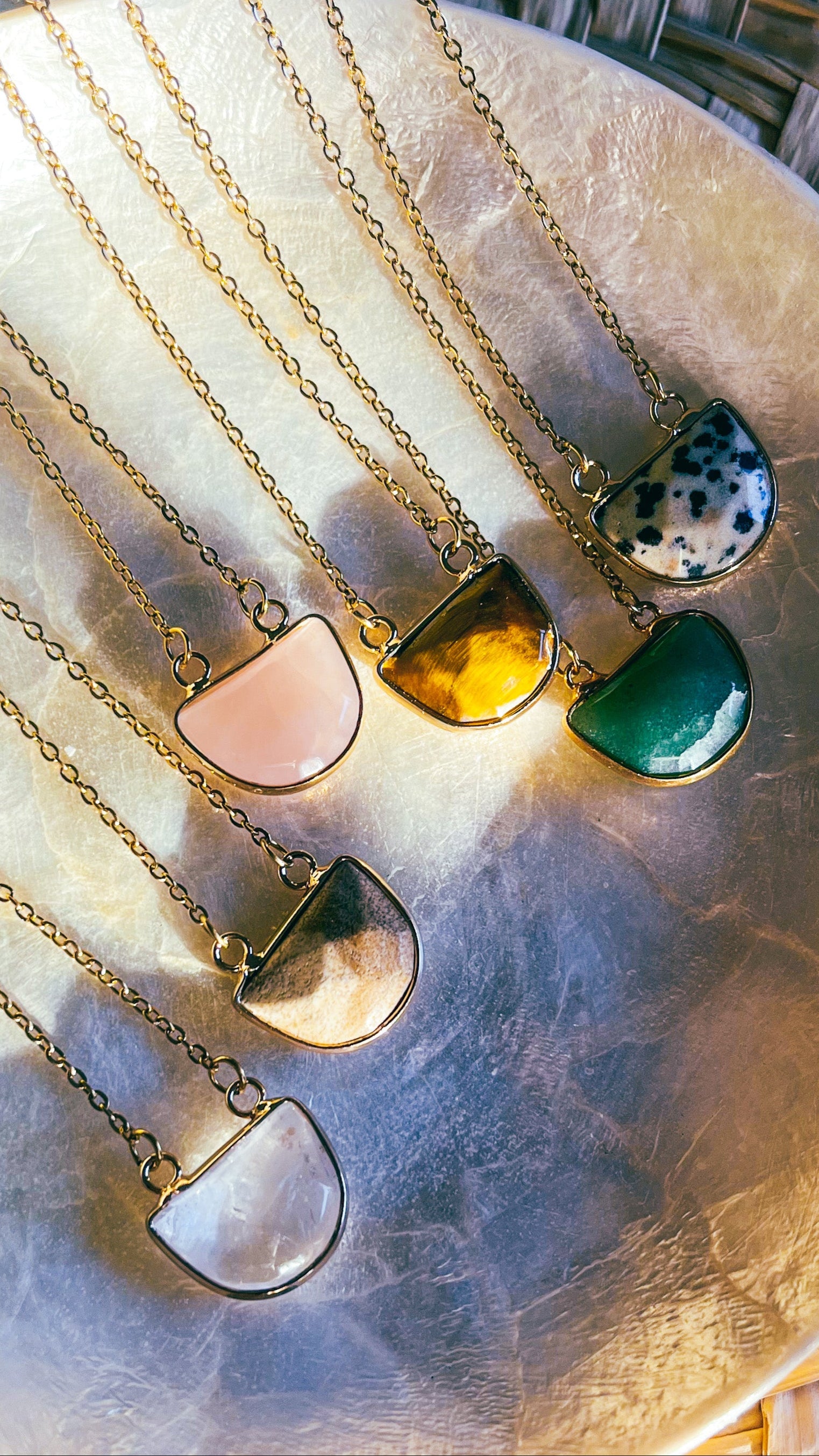 Set of necklaces with colorful pendant designs on a textured surface