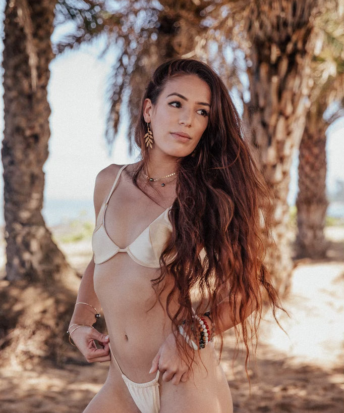Woman in a white bikini standing among palm trees