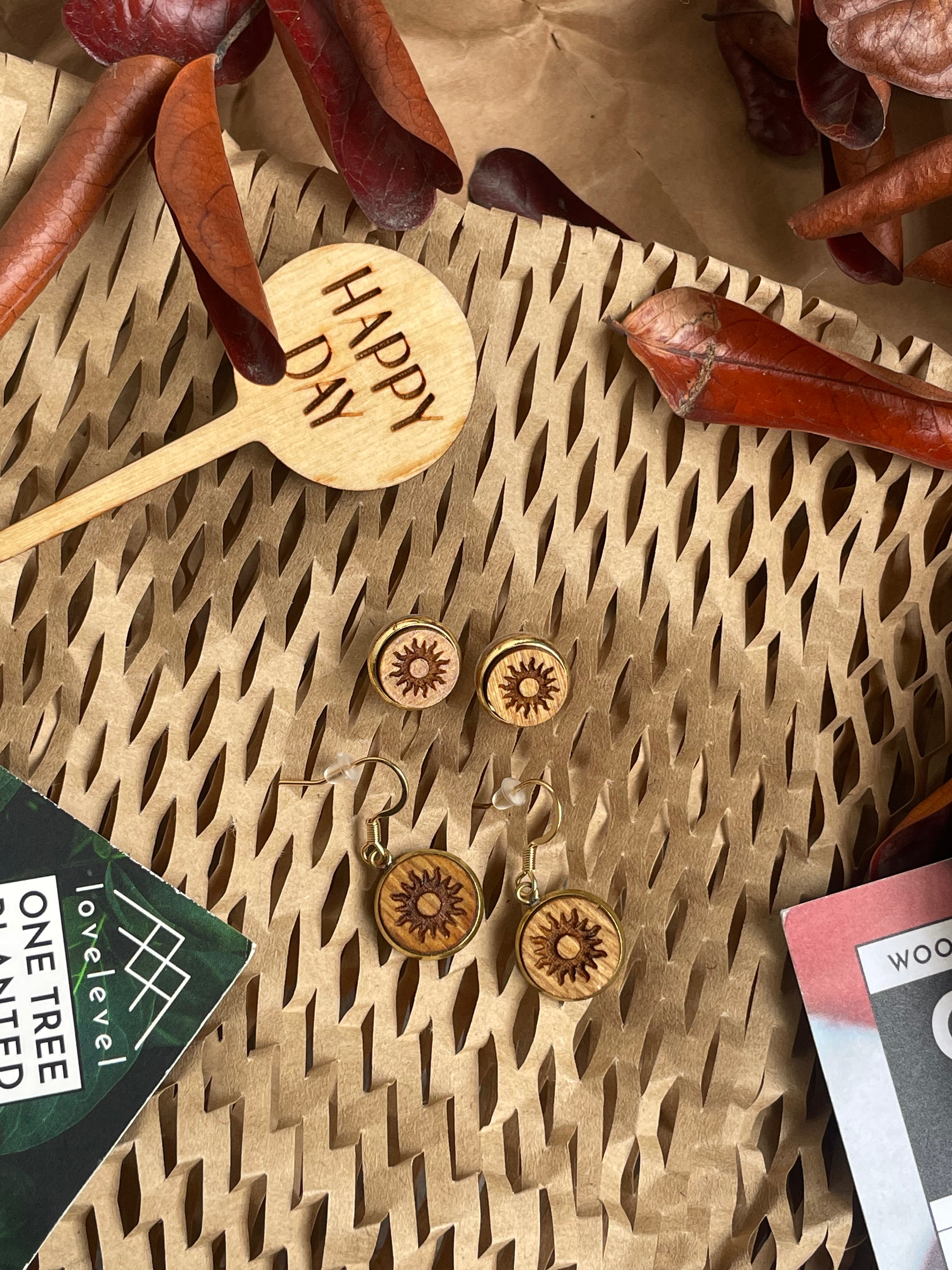 Wooden earrings with a sun design against a natural background.