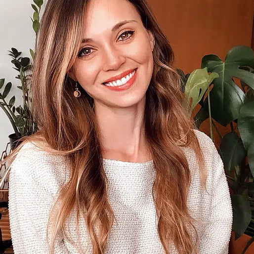 Smiling women in knitted sweater wearing wooden earring against office background.