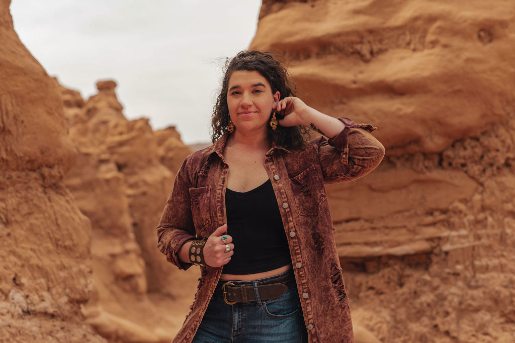 Woman standing in a desert landscape with rock formations.