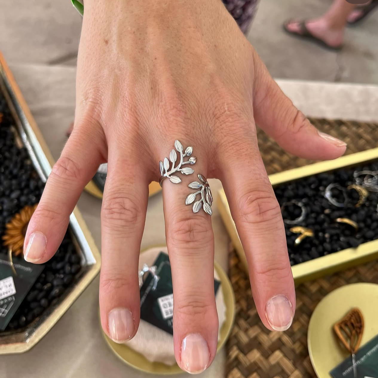 Hand wearing a silver leaf ring with a blurred background