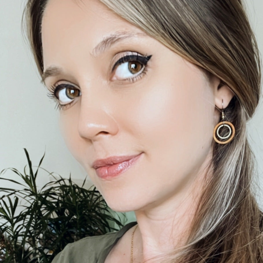 Light haired woman wearing wooden hoop earring with a metal ring in the hoop.