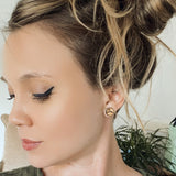 Woman with messy bun wearing wooden stud earring with a mountain peak etched into it.