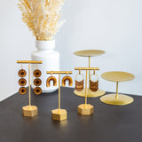 Wooden earrings on gold stands in front of a decorative background