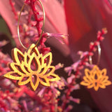 Wooden lotus-shaped earrings on a dark pink leaf background