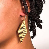 Wooden geometric earring worn by a person with braided hair on a white background
