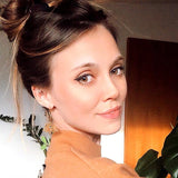Smiling woman wearing wooden lotus flower earrings with her hair in a bun.