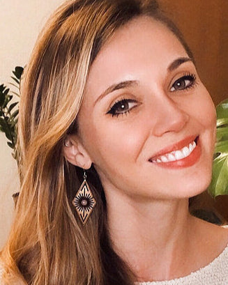 Woman wearing a diamond-shaped wooden earring with a blurred background