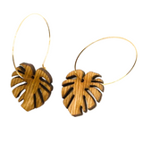 Wooden leaf-shaped earrings on gold hoops against a white background