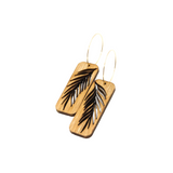 A pair of wooden earrings with a palm leaf design, featuring gold-plated stainless steel hoops.