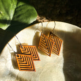 Two pairs of wooden geometric diamond earrings sitting in a stone bowl.