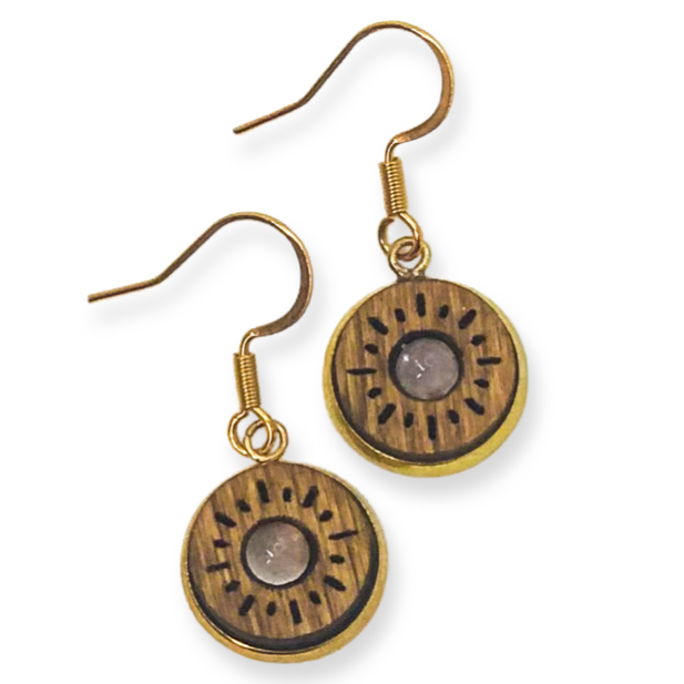 Pair of gold earrings holding a wooden disc with circular designs on a white background