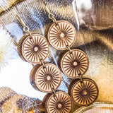 Wooden circular earrings on a gold and black textured background