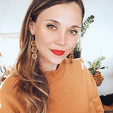 Smiling woman wearing circular wooden earrings and an orange sweater