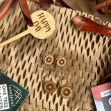Wooden earrings with a sun design against a natural background.
