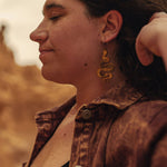 Woman wearing wooden snake earrings with a blurred natural background