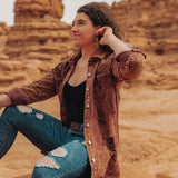 Woman sitting on a rock in a desert landscape with red rock formations.