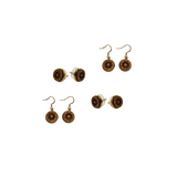 Wooden earrings with a sun design as both studs and dangles in a white space.