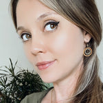 Light haired woman wearing wooden hoop earring with a metal ring in the hoop.