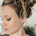 Woman with messy bun wearing wooden stud earring with a mountain peak etched into it.