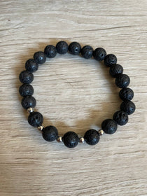 Lava stone bracelet with 5 silver beads against a wooden background.