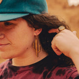 Woman in the desert wearing a blue cap and large wooden cactus earrings.