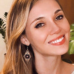 Woman wearing a diamond-shaped wooden earring with a blurred background