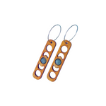 Wooden earrings with moon patterns cut out surrounding a moonstone gem.